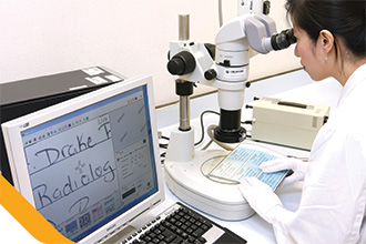 化验师使用显微镜鑑辨文件真伪。