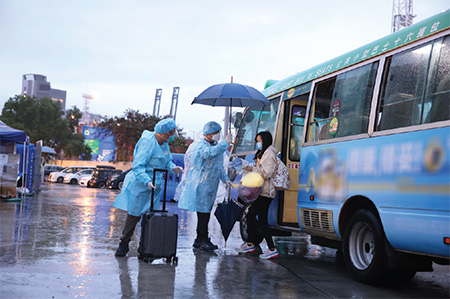 保安局特遣隊成員在大雨中迎接一名抵達方艙社區隔離設施的確診者，並協助其辦理入住登記手續。