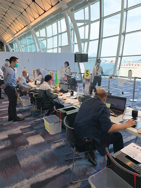 衞生署工作人员在香港国际机场临时样本採集中心处理回港易旅客的检疫手续。