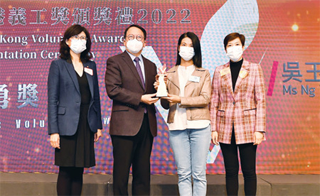高級關員吳玉蘭女士(右二)，從政務司司長陳國基先生(左二)手上接過「義勇獎」。