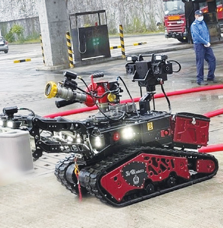 Firefighting robot operator using thermal imaging display function at remote control to monitor fire situation and carry out firefighting work.