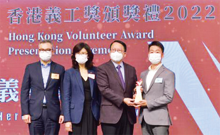政务司司长陈国基先生( 右二) ， 颁发「义勇奖」给消防区长李浩贤先生(右一)。