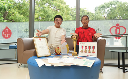 關先生(右)和杜先生(左)展示多年來捐血所獲得的獎牌、捐血卡和相關的剪報，並互相分享捐血的心得。