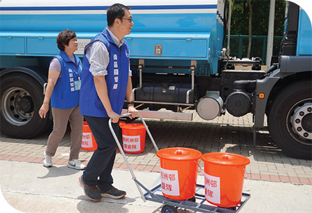 關愛隊成員在鴨脷洲邨暫停食水供應期間為居民運送食水。
