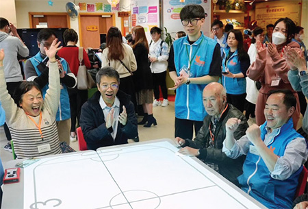 公務員事務局常任秘書長梁卓文先生(左二)及政府資訊科技總監黃志光先生(右一)與長者一起參與有趣的互動虛擬曲棍球。