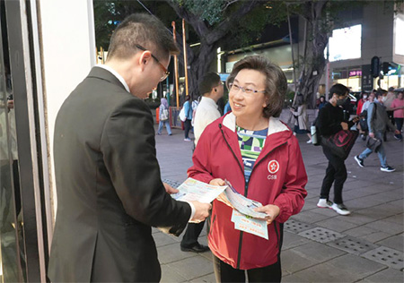 公務員事務局局長楊何蓓茵女士(右)向一名店鋪負責人派發宣傳單張。