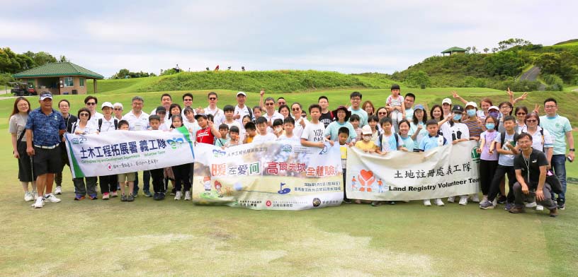 Group photo of the volunteer team and children at the Real Grass Practice Tee.